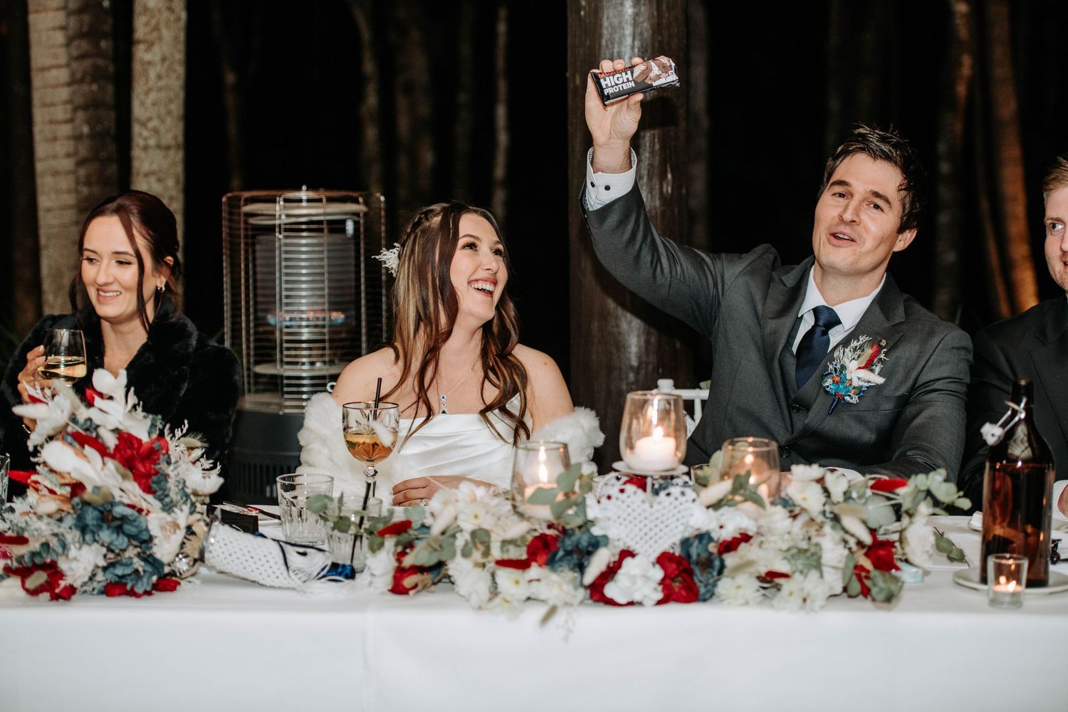 Wedding party raises glasses in celebratory toast at decorated head table.