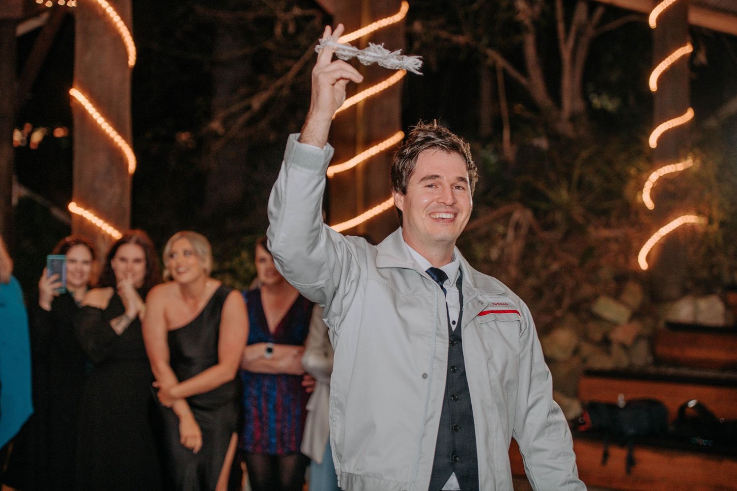 Wedding guest raises glass in celebratory toast during evening reception.