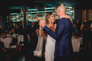 Couple sharing their first dance in an elegant reception venue with dramatic lighting.