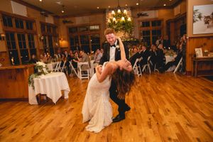 Couple performing a romantic dip during their wedding dance on a hardwood floor.