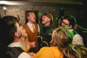 Wedding guests laughing and celebrating together under green party lights.