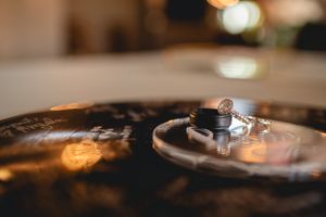 Close-up artistic shot of wedding rings on textured surface with bokeh lighting effects.