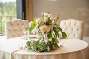 An elegant white and green floral centerpiece arrangement on a round table.