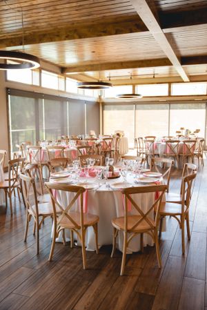 Elegant wedding reception venue with round tables, crossback chairs and wooden beam ceiling details.