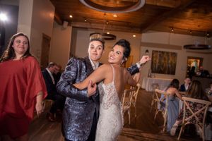 Lively reception dance party in rustic indoor venue with wood ceiling details.