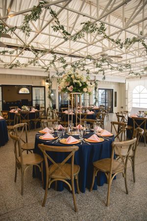 Elegant wedding reception setup with navy tablecloths and hanging greenery decor.