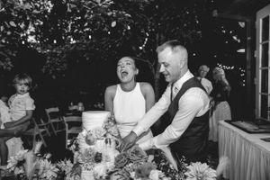 Couple sharing a joyful moment while arranging flowers at their wedding reception buffet table.