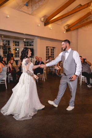 A couple sharing their first dance in a reception hall with exposed wooden beams.
