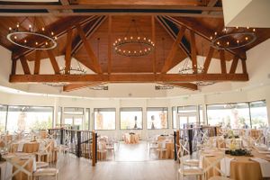 Rustic wedding venue interior with exposed wooden beams and circular string light fixtures.
