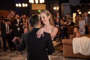 Romantic couples dancing at an elegant indoor wedding reception with soft lighting.