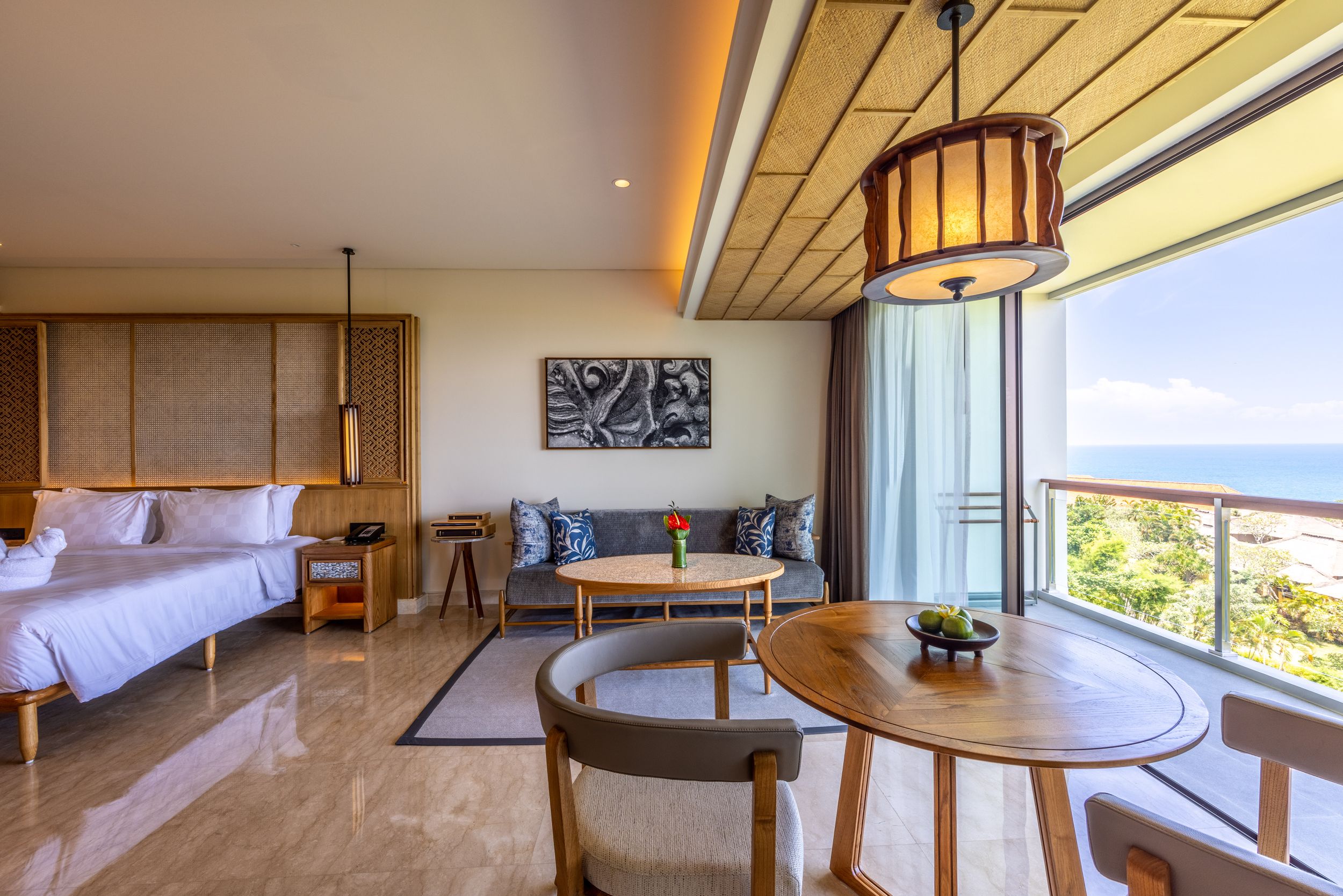 Upscale hotel suite living area with dining table, sofa, and stunning ocean views.