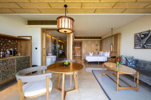 Modern hotel suite interior with wooden dining set, sofa, and ambient lighting.