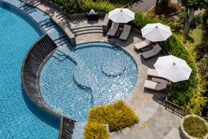 Luxury resort pool with curved edges and white parasols arranged along the deck.