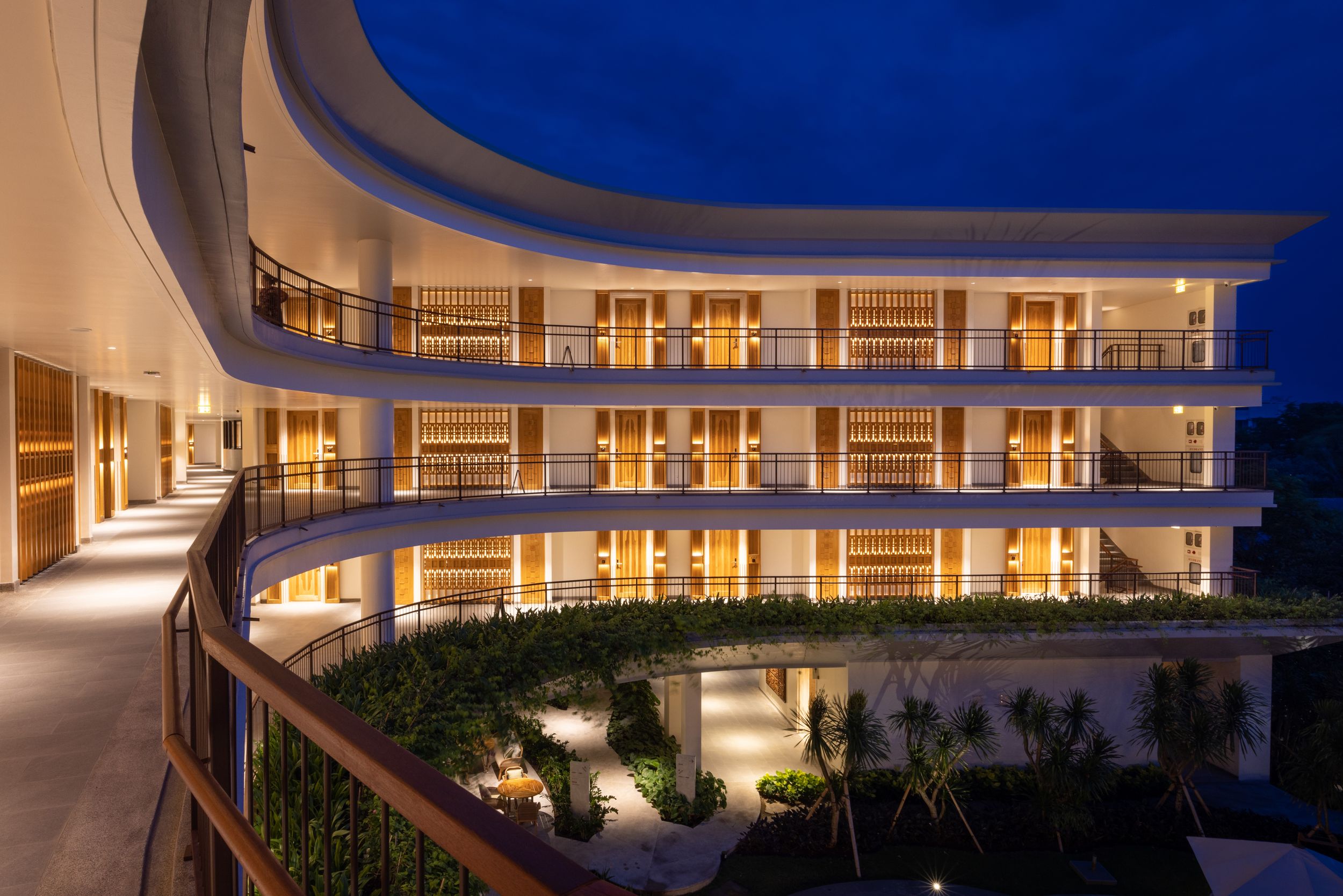 Modern curved building exterior illuminated at night with reflective pools.