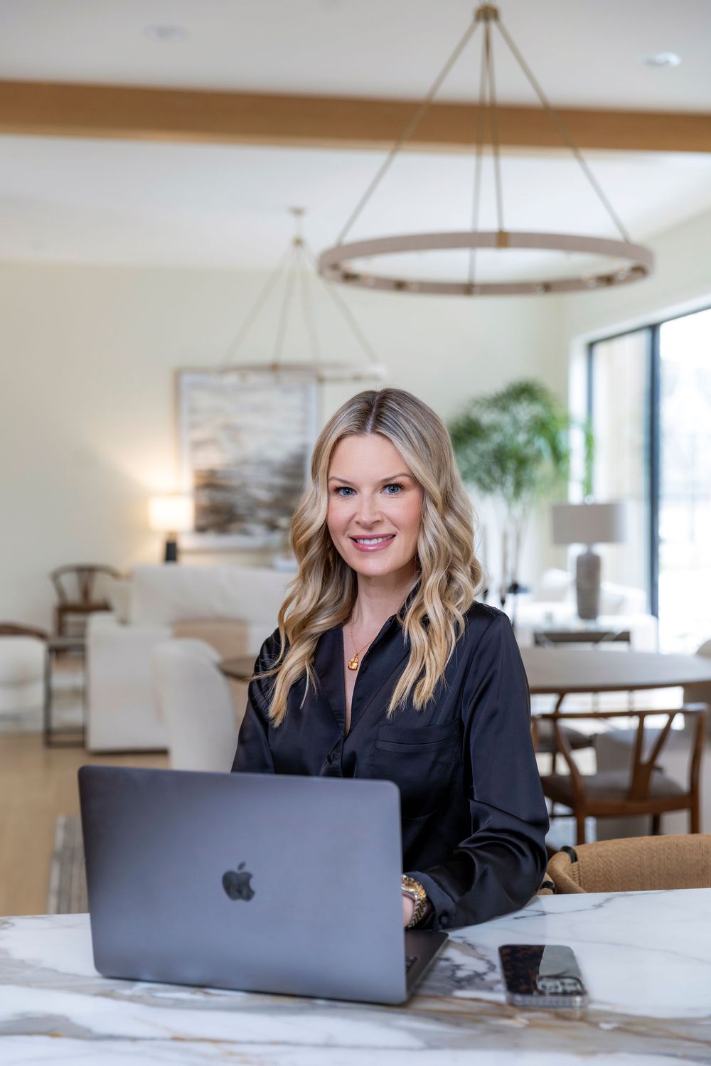 Person working on laptop in bright modern office space with pendant lighting and rustic decor.