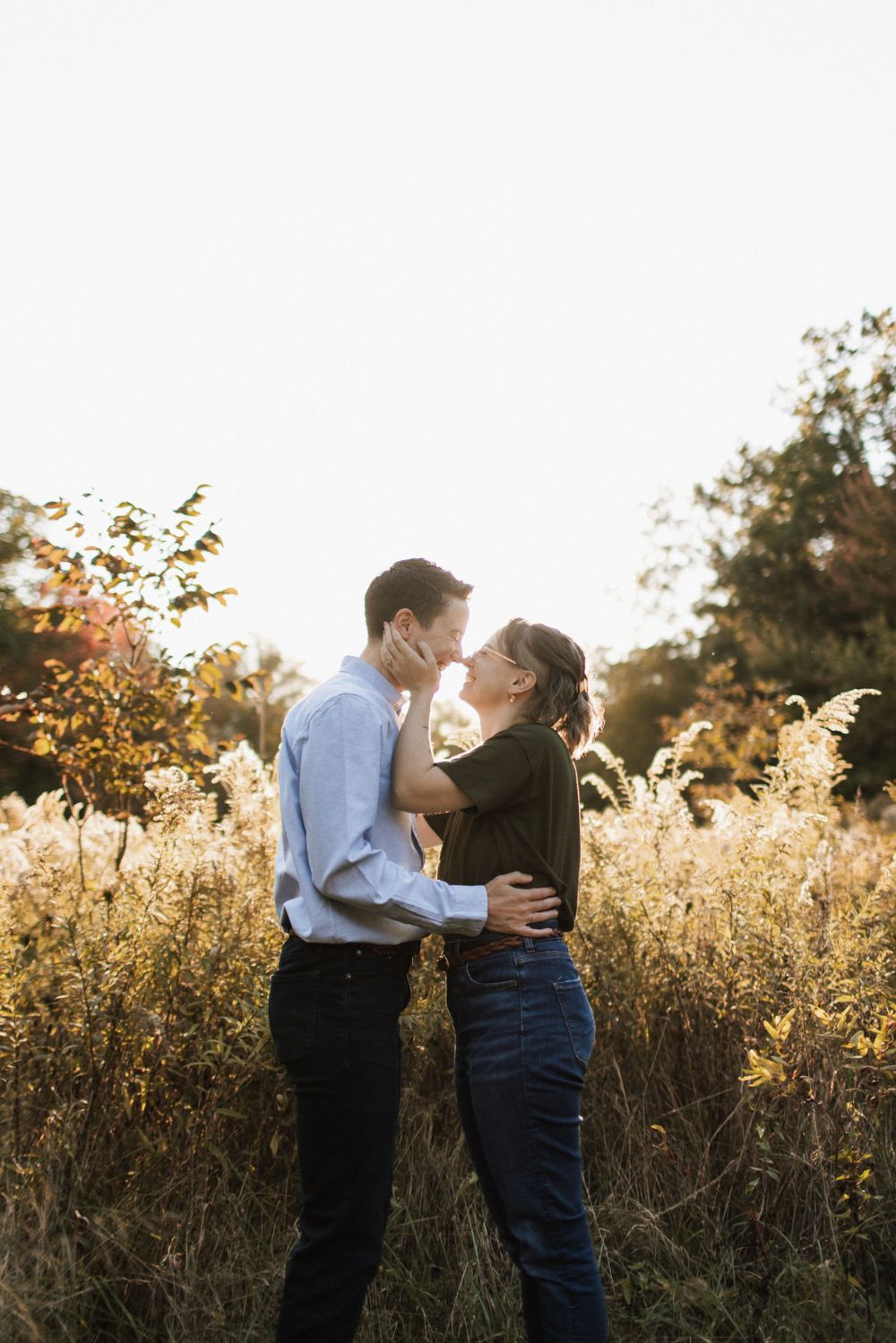 Couple embracing and about to kiss in a golden autumn meadow at sunset.