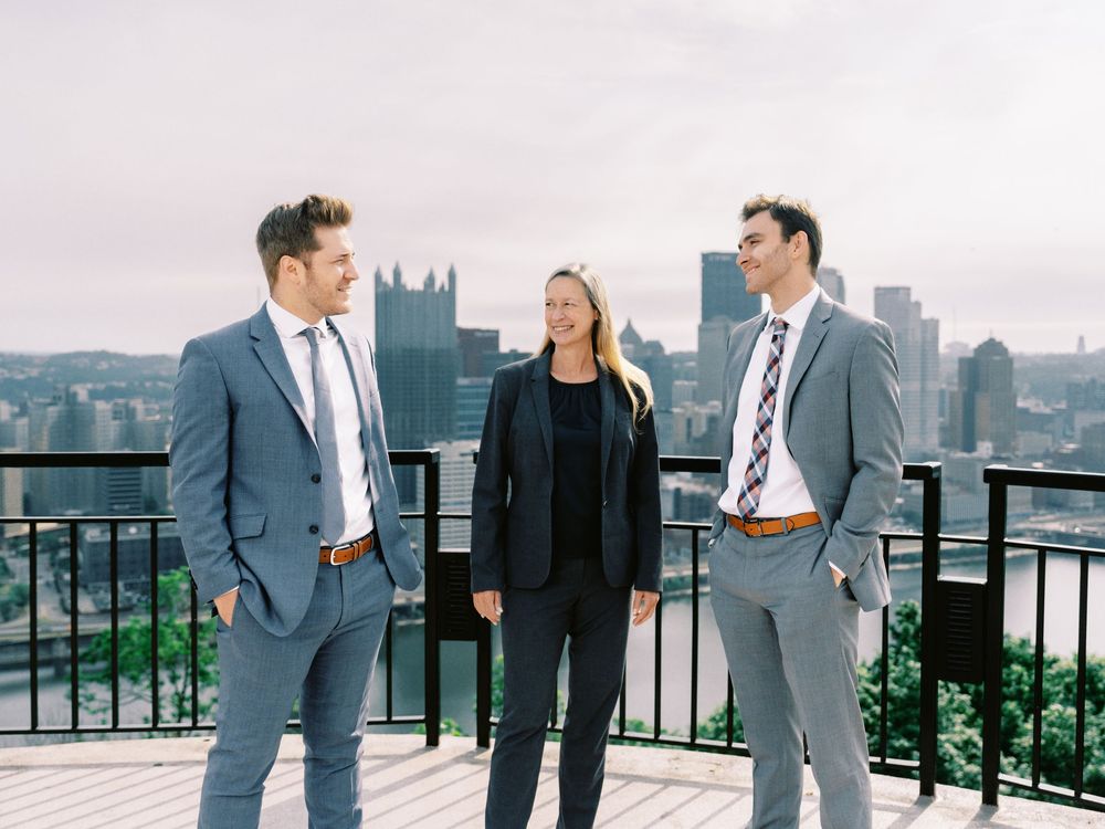 Business professionals having a conversation on a rooftop terrace overlooking a cityscape with cathedral spires.
