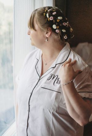 Close-up of white monogrammed bridal robe with floral details in hair.