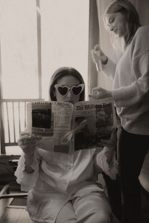 Black and white photos of bride reading newspaper while getting ready for wedding.