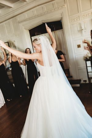 A sequence of photos showing a bride in a flowing white wedding gown and veil twirling gracefully on a dark hardwood floor.