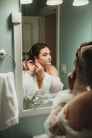 Getting ready scene at vanity mirror with bright overhead lighting.