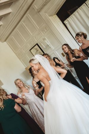 Wedding party members in formal attire gather around a bride in a flowing white gown.
