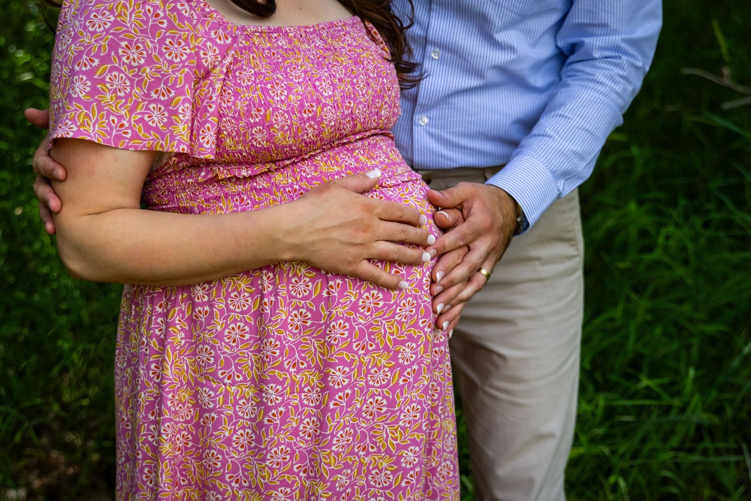 a couple holding her baby bump.