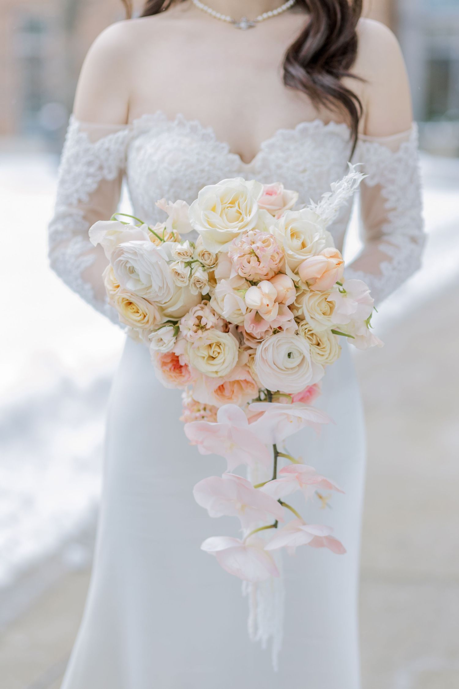 Elegant bridal bouquet featuring white roses and blush pink flowers with delicate orchids.