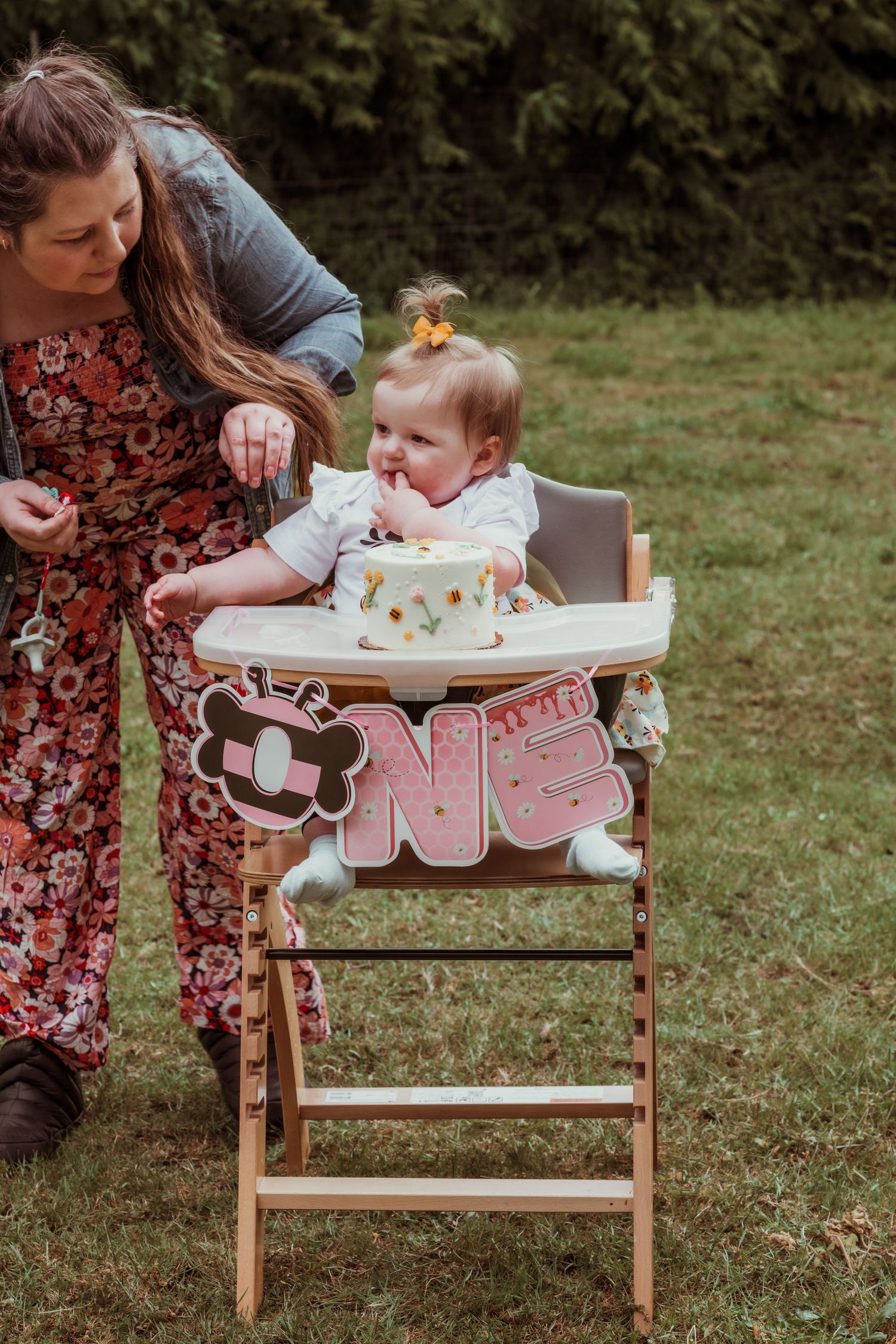 Mom helps her one-year-old with a smash cake at an outdoor first birthday session at Enchanted Farms in Duvall, WA.