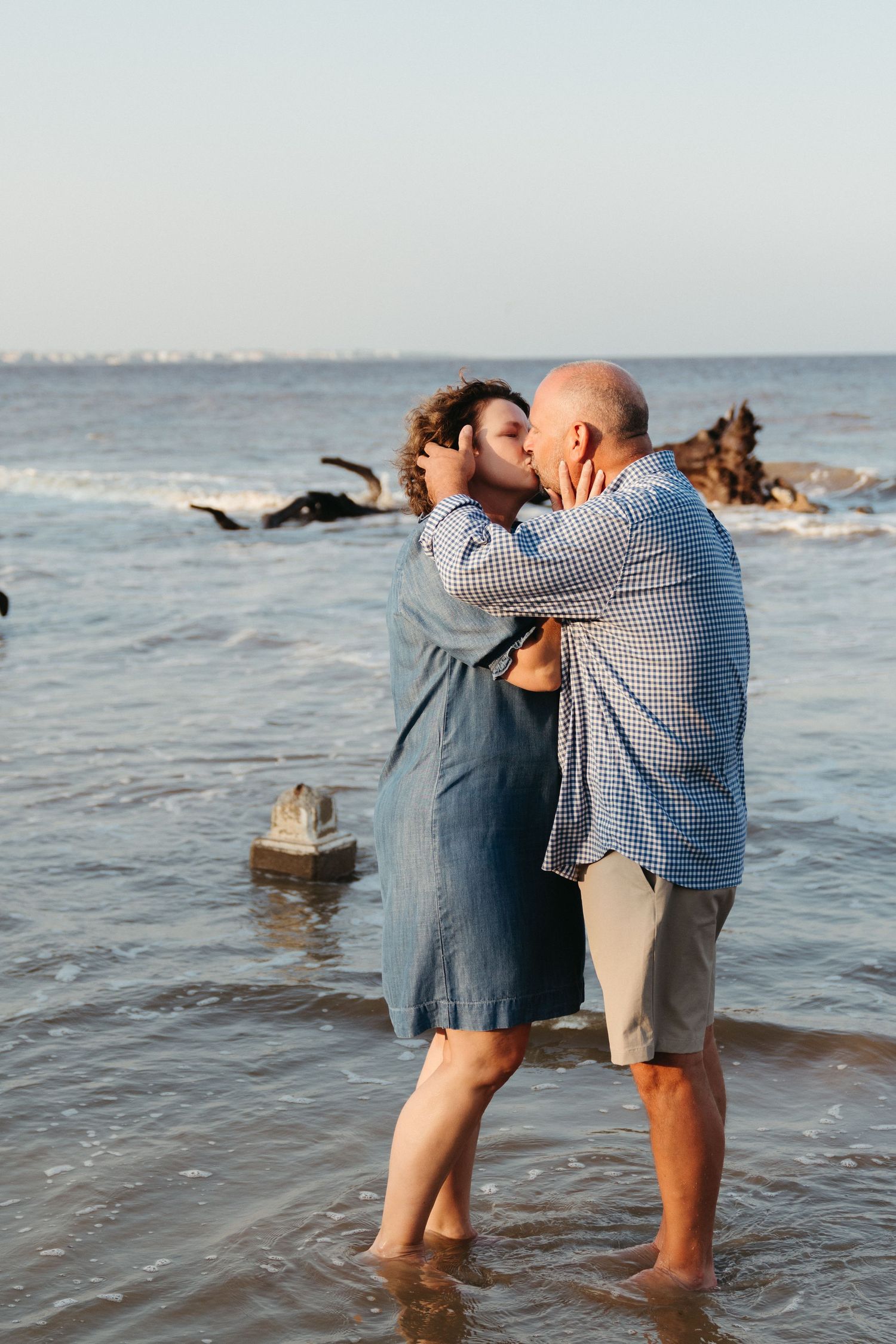 Couple kissing at the ocean’s edge during a couples portrait session on Driftwood Beach, Jekyll Island with photographer Lindy Rebro