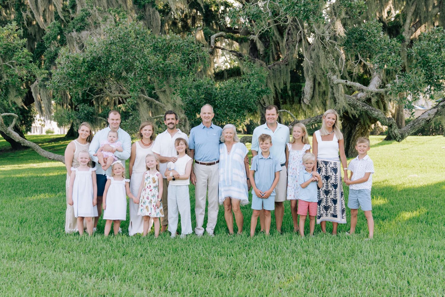 Extended family portrait beneath Spanish moss-covered oak trees, showing grandparents, parents, and children together.