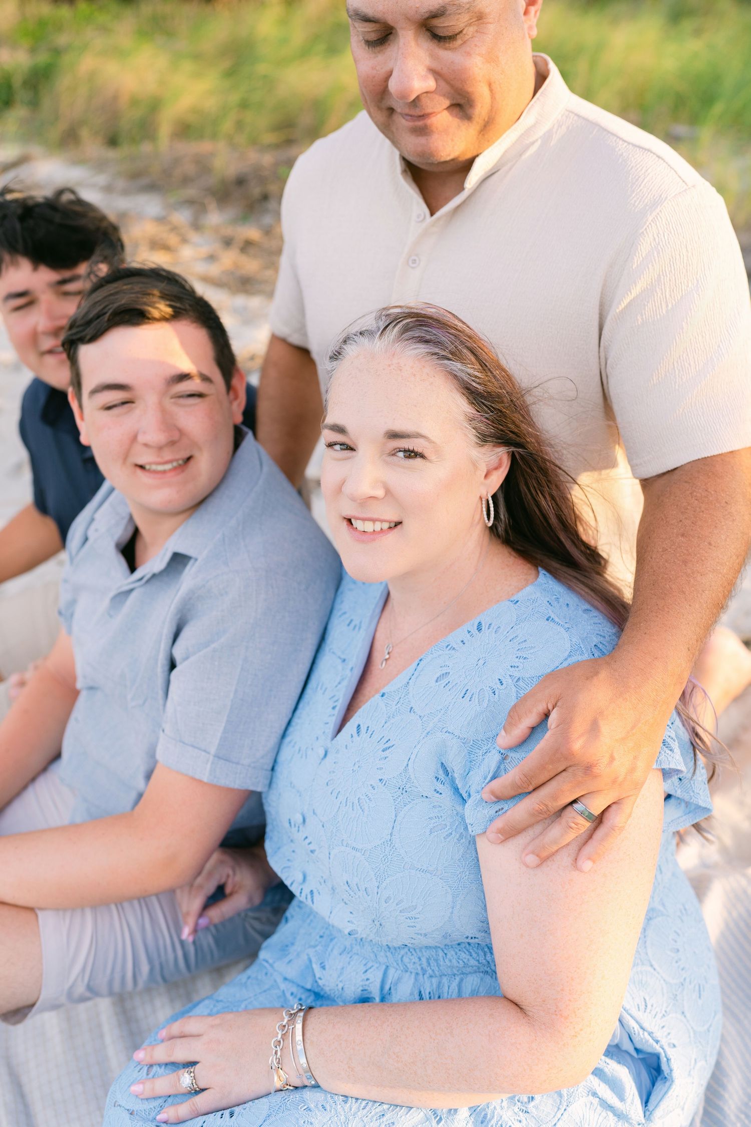 Close-up family portrait with a mother in a blue dress, photographed during a beach session in south Georgia with Lindy Rebro Photo.