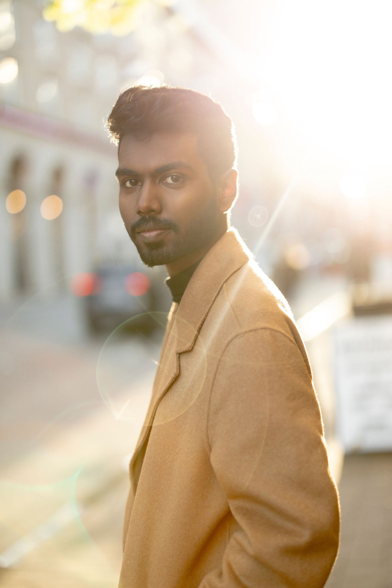 Portrait of a person in a camel coat with golden sunlight creating a warm backlit glow.