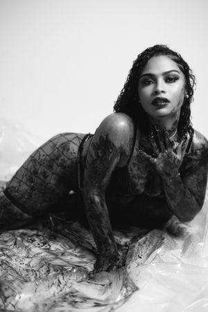 Artistic black and white fashion photo showing model in wet-look styling on light background.