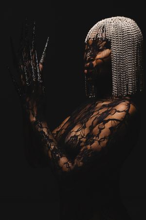 Dramatic portrait with silver braided hair and lace overlay against dark background.