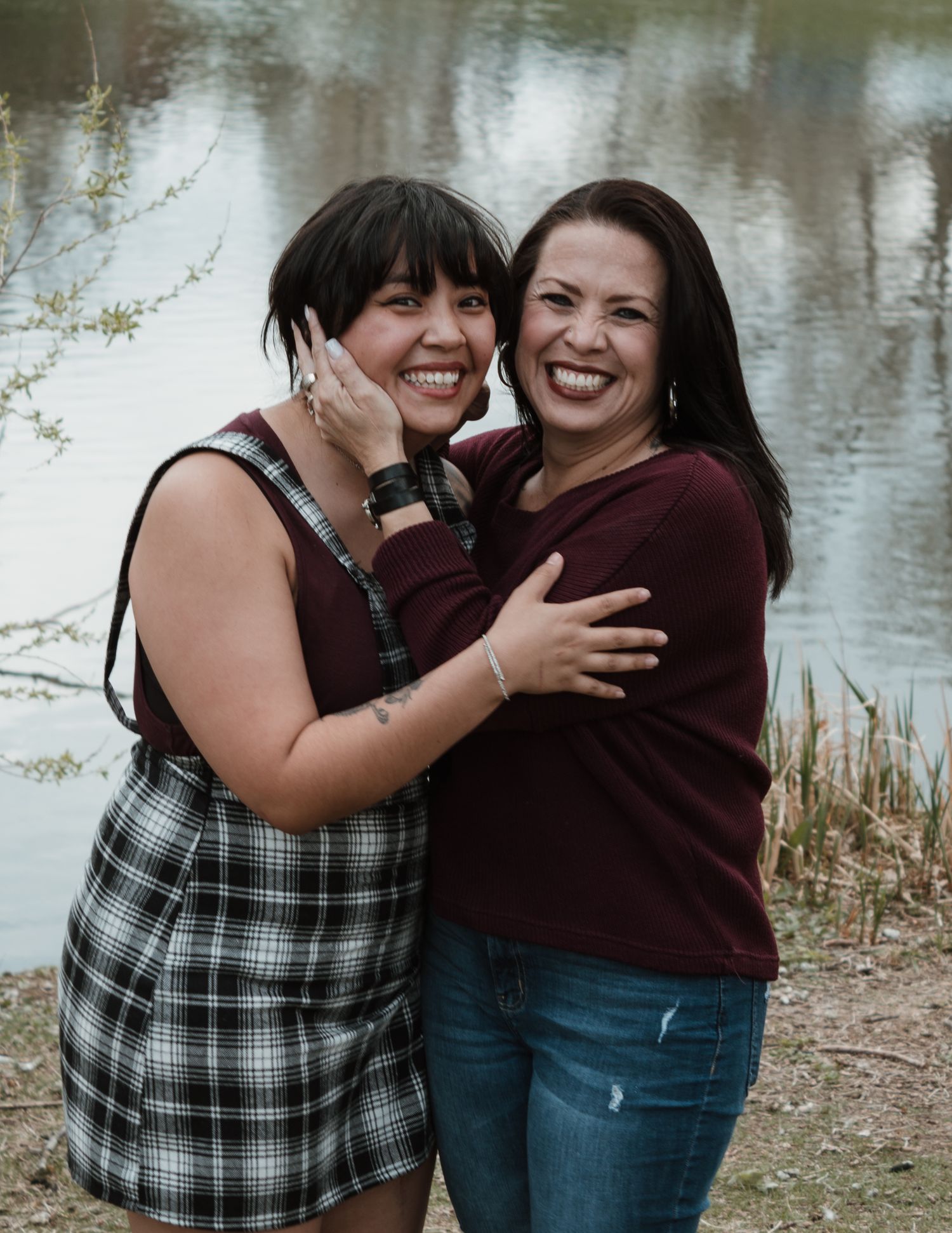 Two friends sharing a joyful moment and laughing together by a lake.