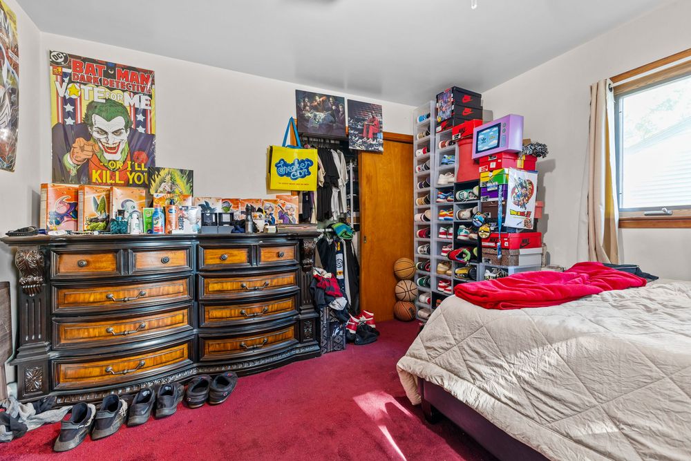 Carpeted bedroom with comic book posters, wooden dresser, and collectibles.