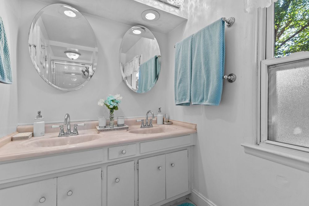 Double vanity bathroom with oval mirrors, dual sinks, and natural window light.