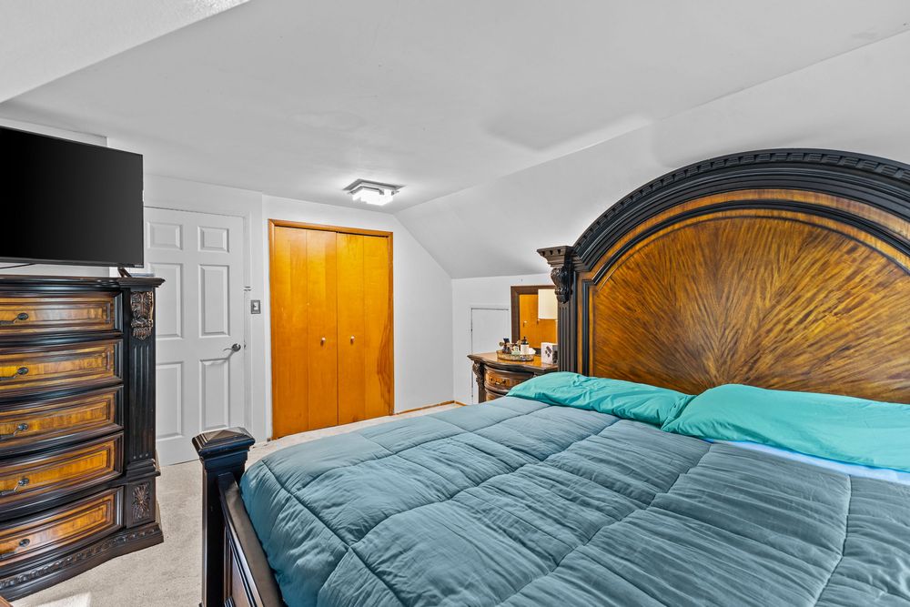 Cozy bedroom with sloped ceiling, wooden headboard, and teal comforter.