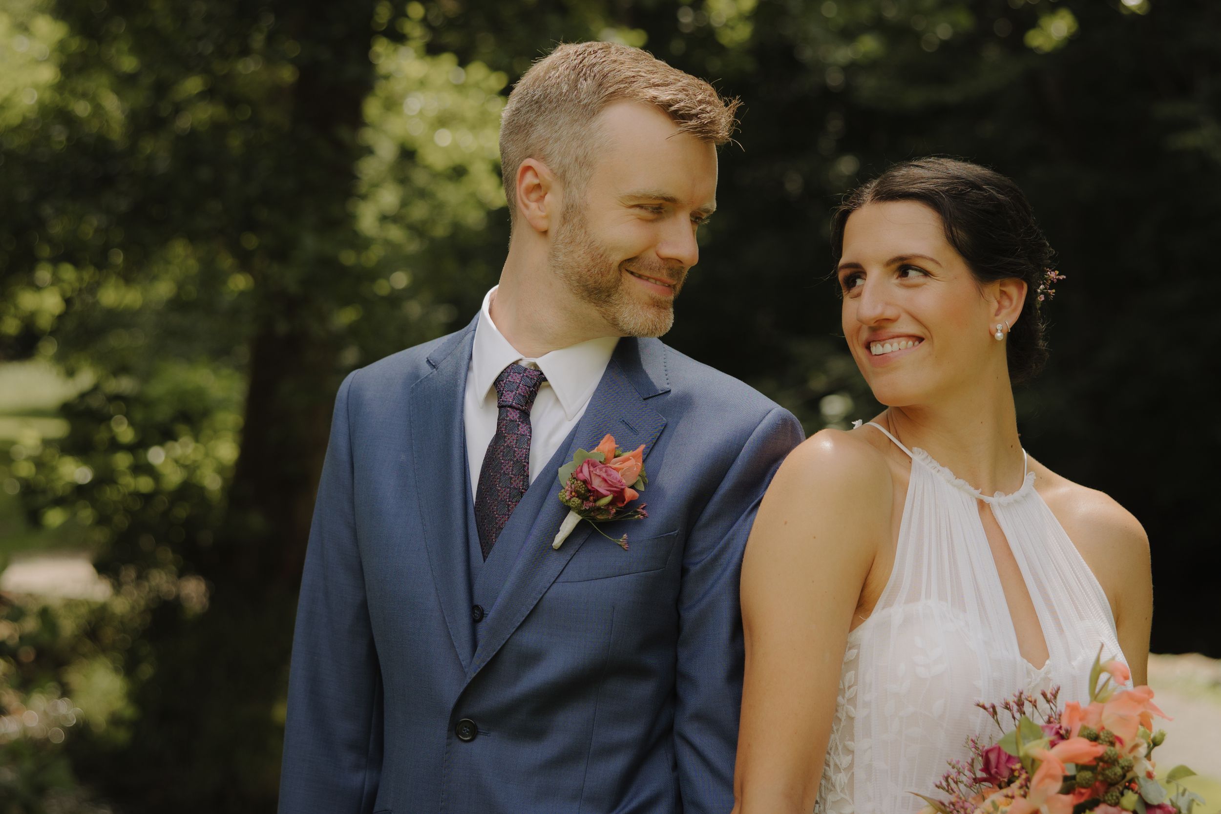 Black and white candid photo of newlyweds sharing joyful moment at outdoor ceremony.