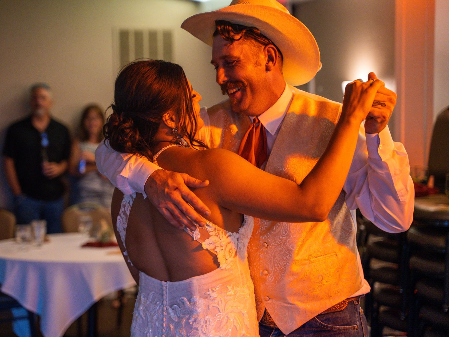 Couple dancing together at formal event under warm lighting.