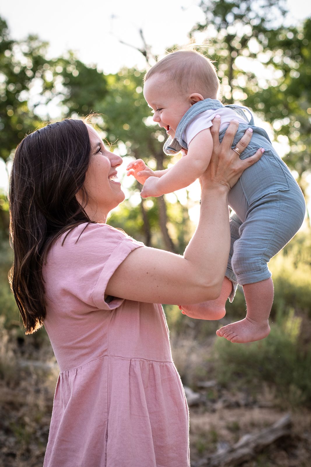 Beautiful outdoor family photography; mom holding baby in the air in sunset landscape; Clarissa Anello