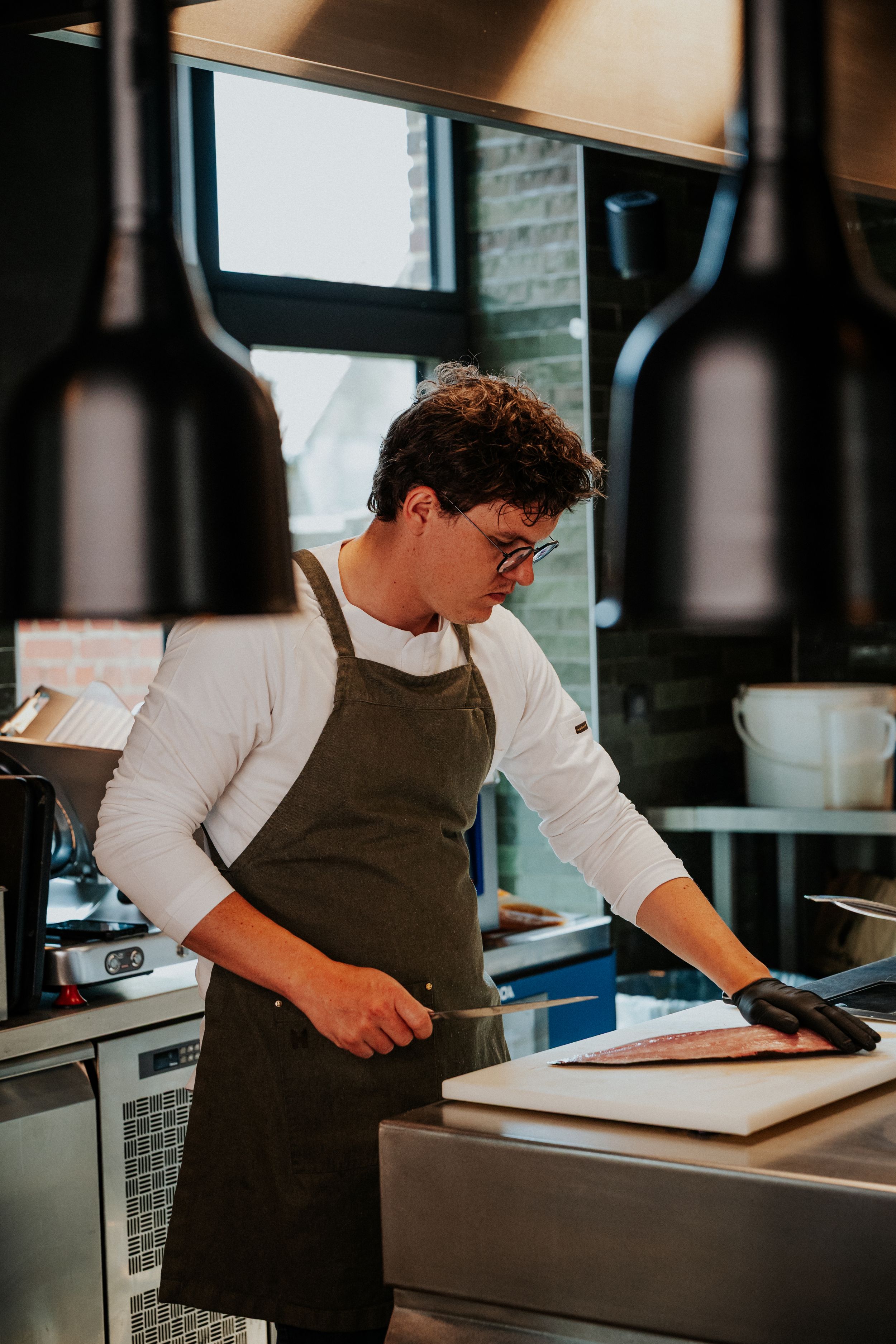 Chef in apron working at restaurant counter.