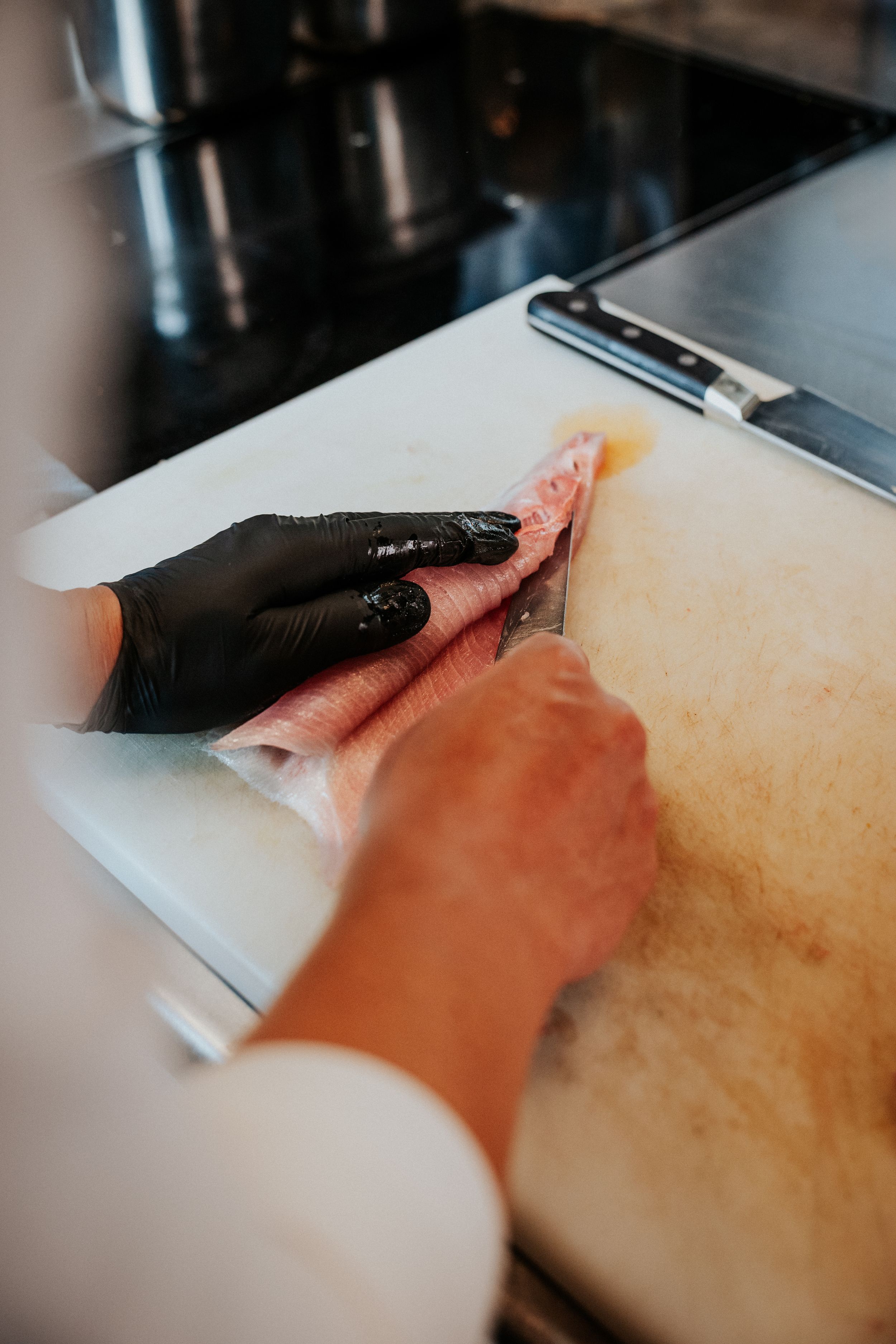 Close-up of hands preparing food on cutting board in professional kitchen.