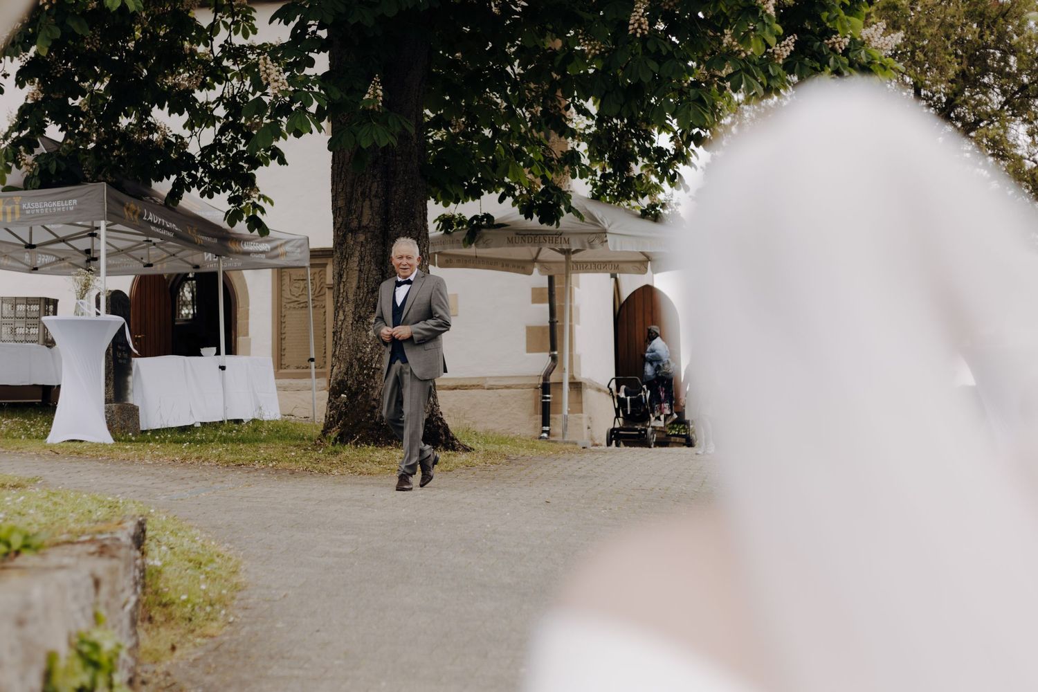 A guest walks along a pathway outside a white wedding venue building.