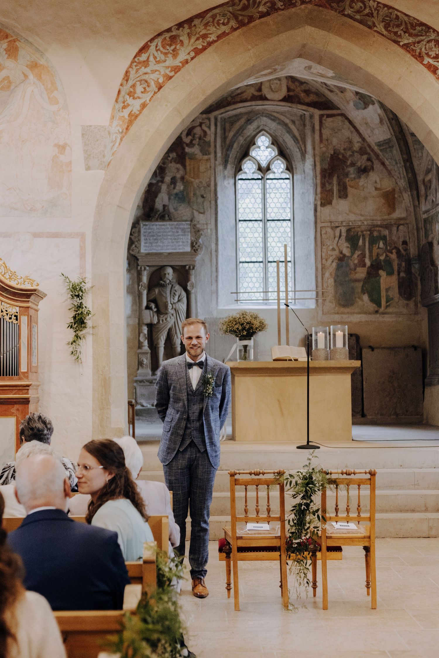 Historic church interior with ornate frescoes and arches decorated for an intimate wedding ceremony.