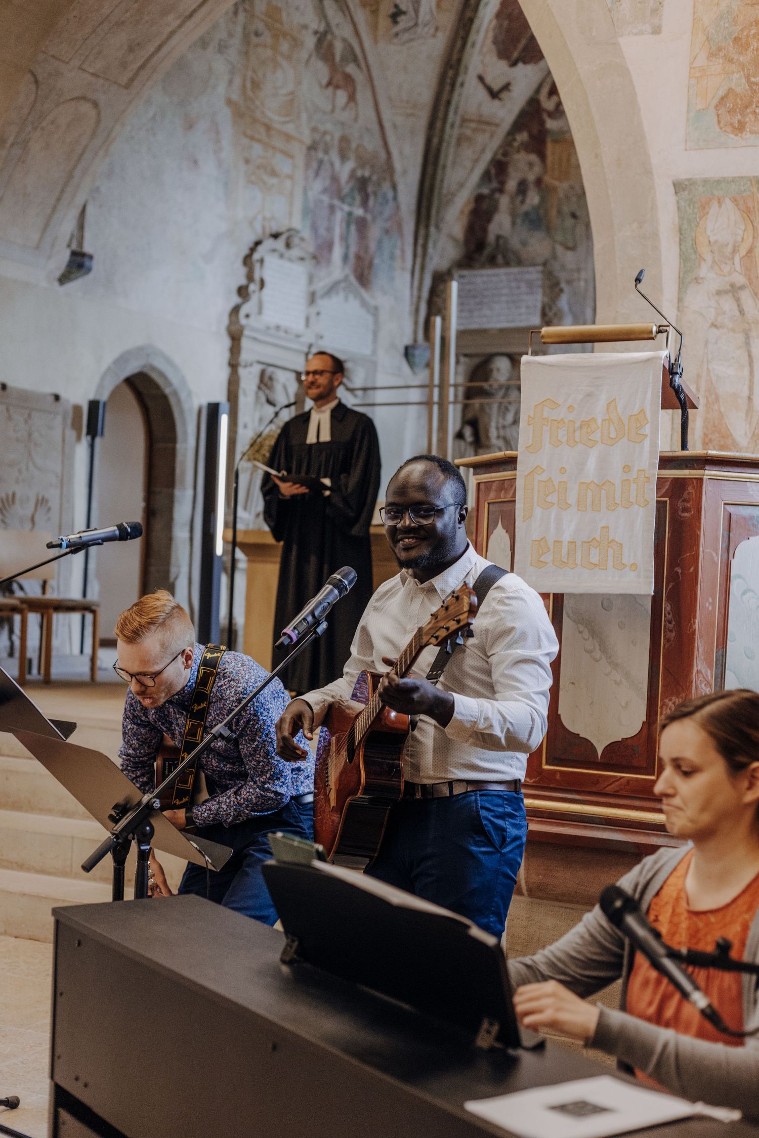 Musicians perform during a church wedding ceremony with acoustic guitar and instruments.