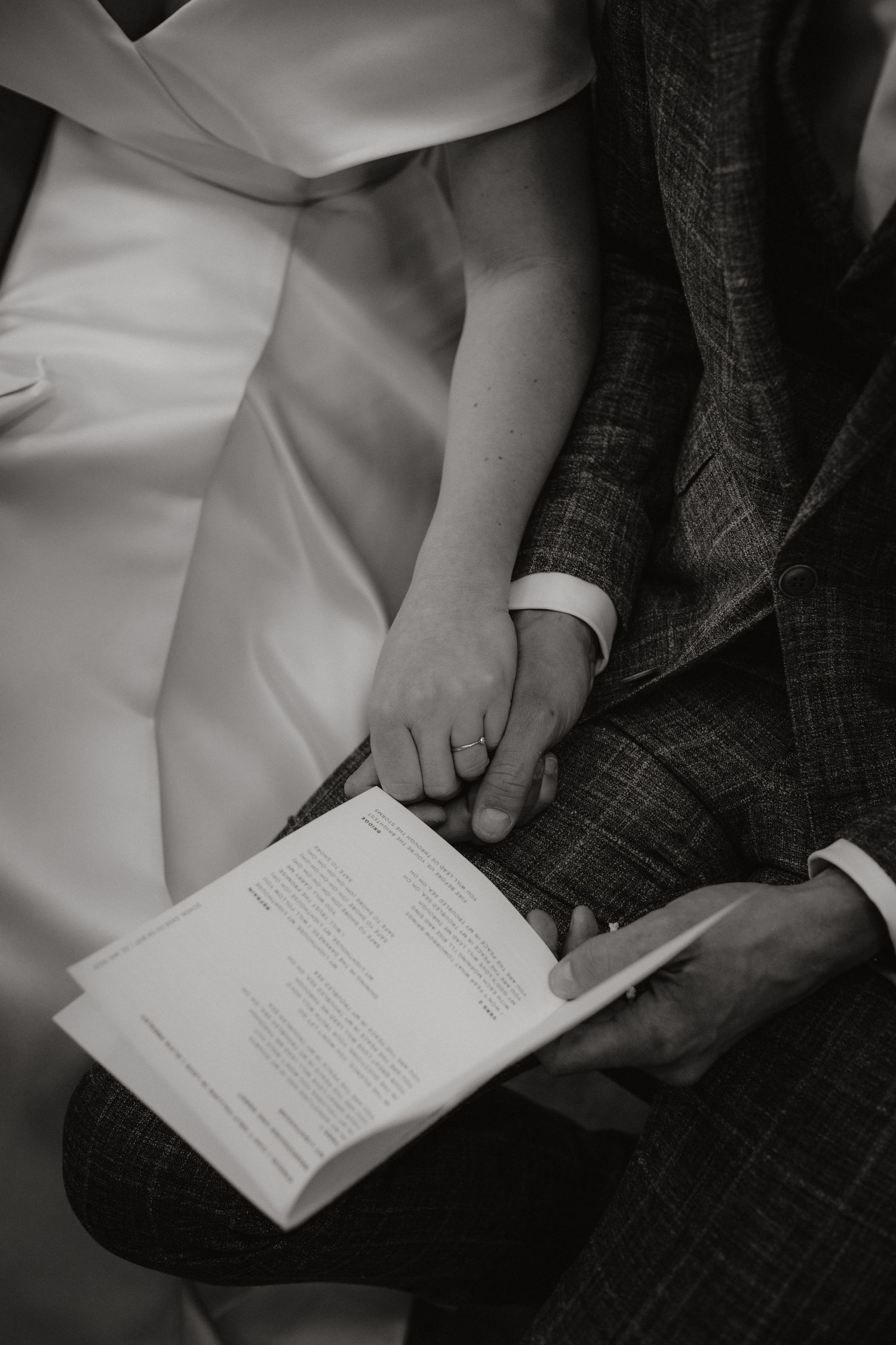 Close-up of hands holding ceremony program book during intimate wedding moment.