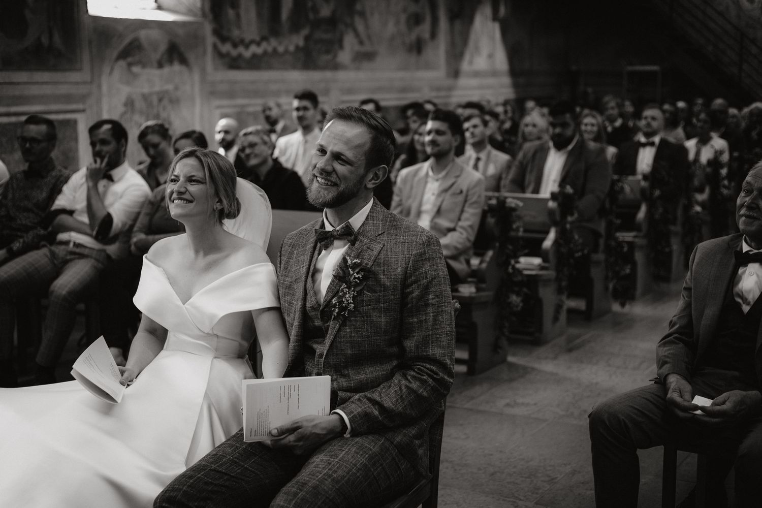 Wedding couple seated in church pews during their ceremony service.