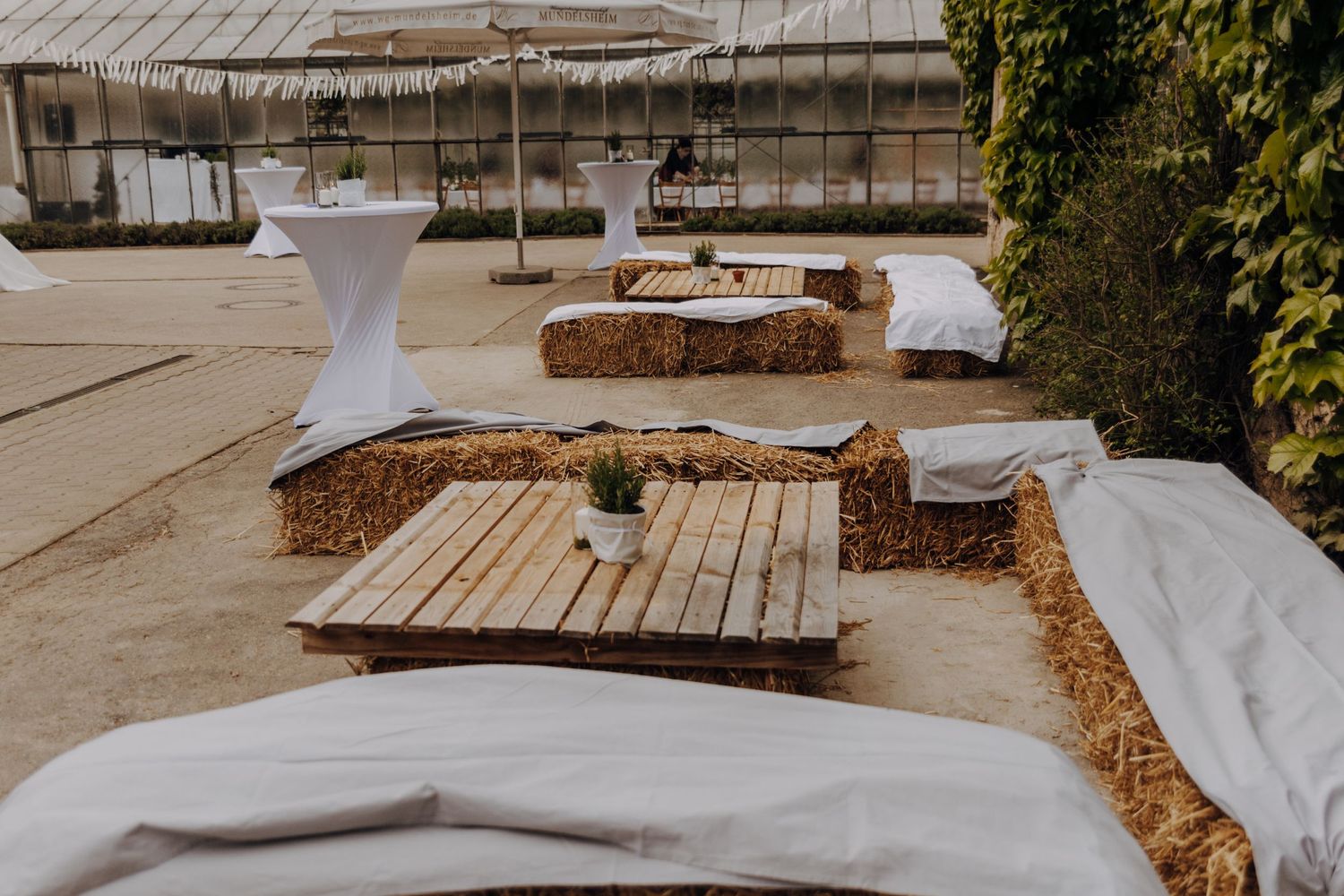 Rustic wedding seating arrangement with hay bales and wooden platforms in an outdoor venue.